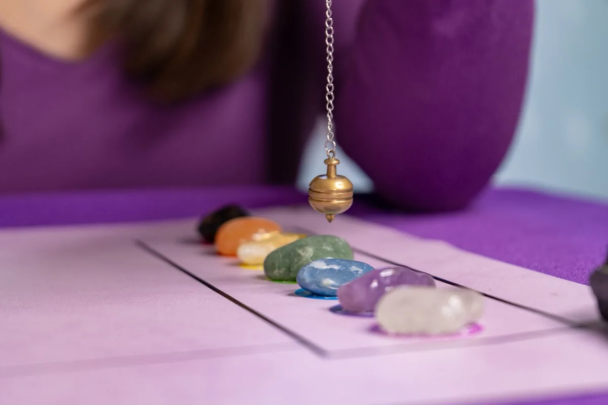 Péndulo dorado sobre una hilera de cristales de colores