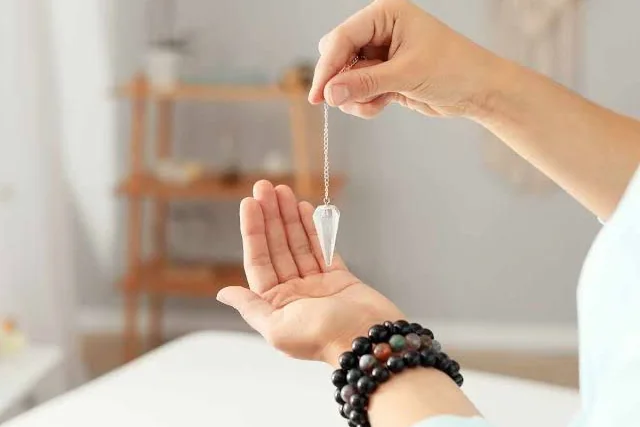 Una mano sosteniendo un péndulo de cuarzo